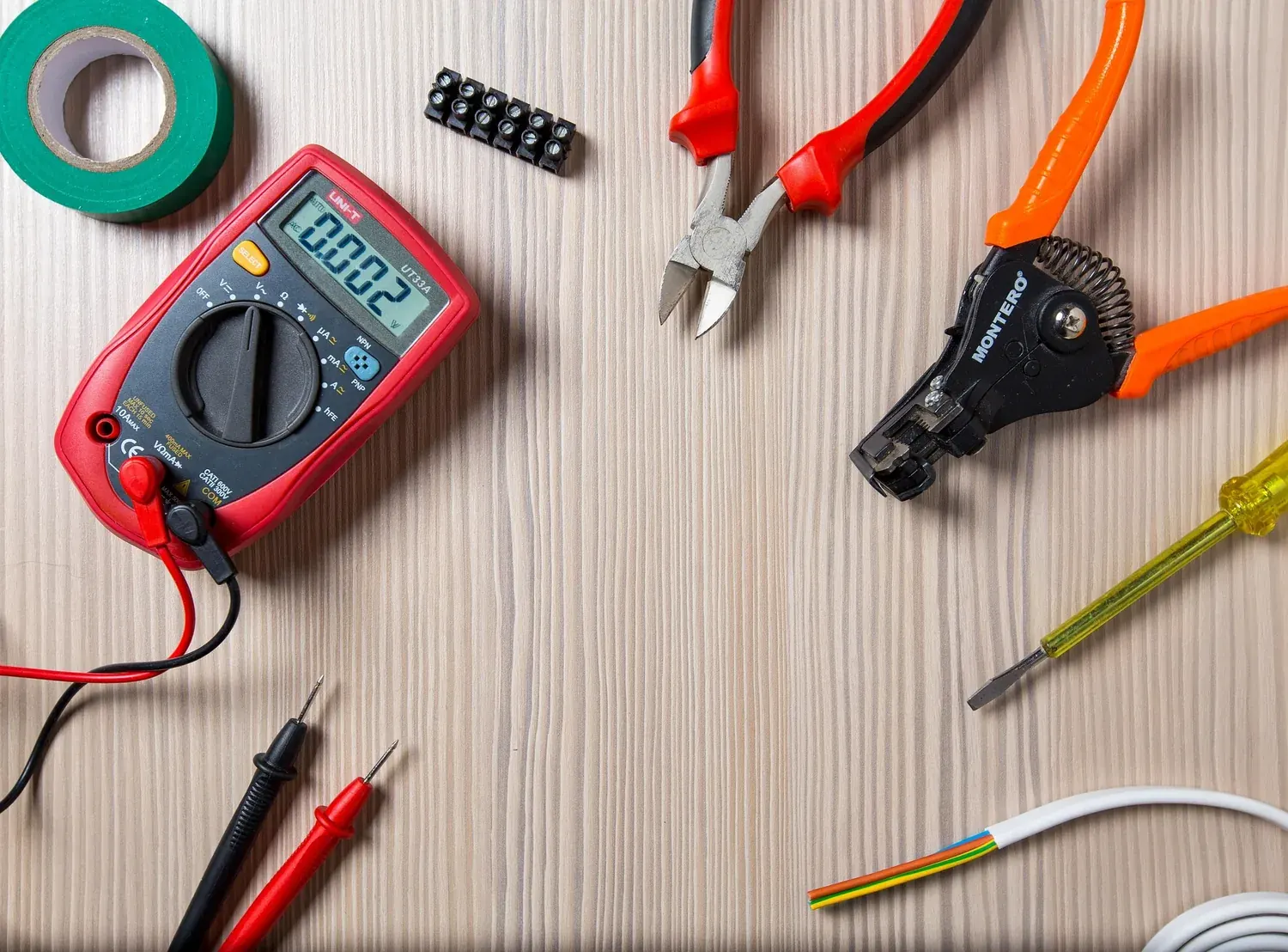 An electrician's tools laid out: multimeter, cutters, and strippers.