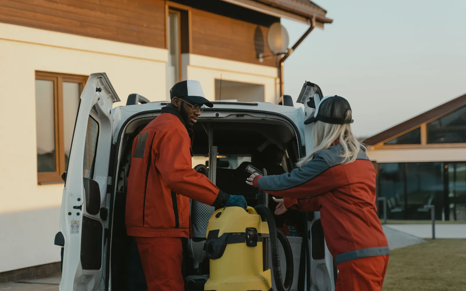 A home-service crew loading their van outside a home at golden hour.